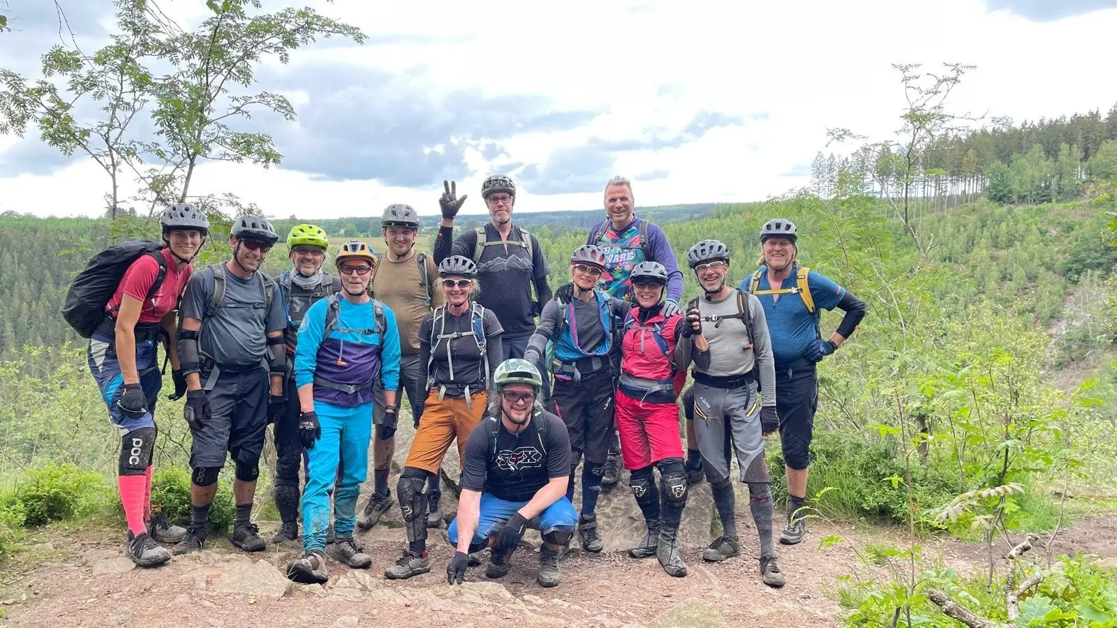 Eine große Gruppe von Mountainbiker*innen posiert gemeinsam auf einem Felsen mit Ausblick. | © DAV Dortmund