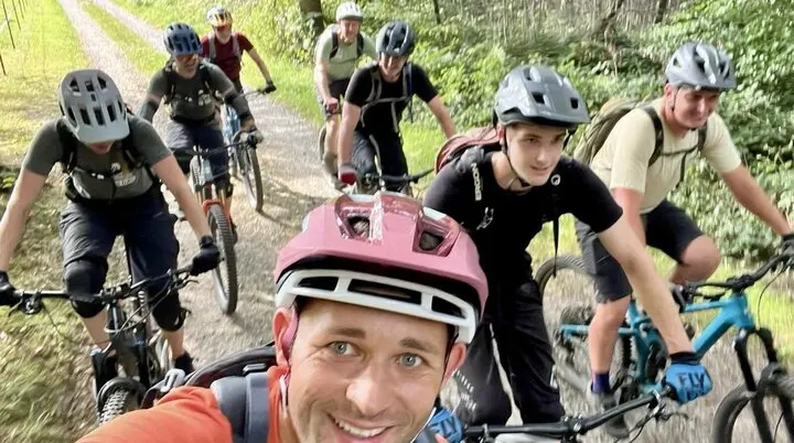 Eine Gruppe von neun Personen auf Mountainbikes, lächelnd bei einer Tour durch den Wald. | © DAV Dortmund