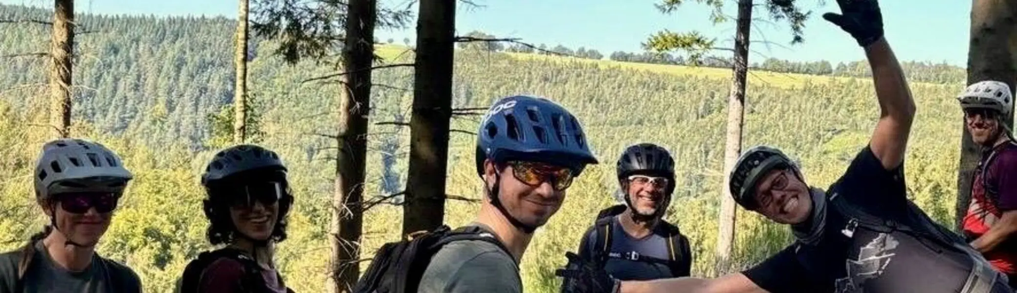 Sechs Biker*innen stehen lachend auf einem Waldweg und posieren für ein Gruppenfoto. | © DAV Dortmund