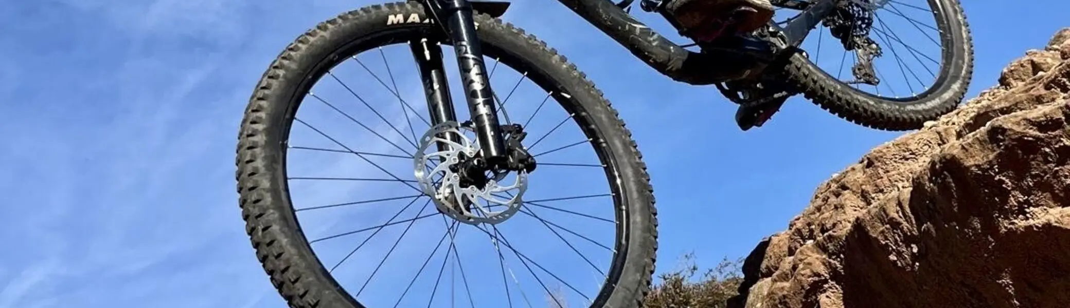 Mountainbiker in voller Schutzausrüstung springt mit dem Fahrrad über felsiges Gelände. | © DAV Dortmund