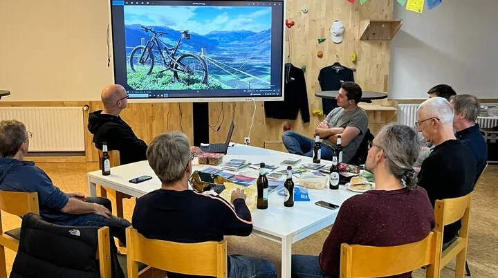 Gruppe von Personen schaut sich eine Mountainbike-Präsentation auf einem großen Bildschirm an. | © dav mtb
