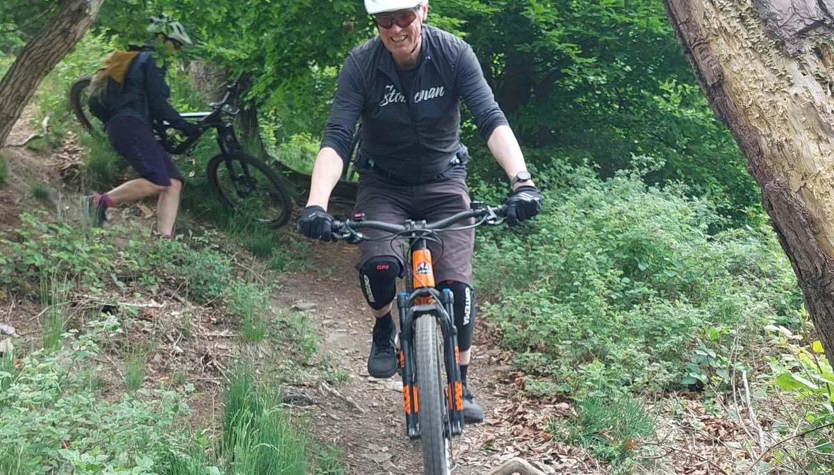 Ein Biker mit weißem Helm fährt vorsichtig eine steinige Passage im Wald hinab. | © DAV Dortmund