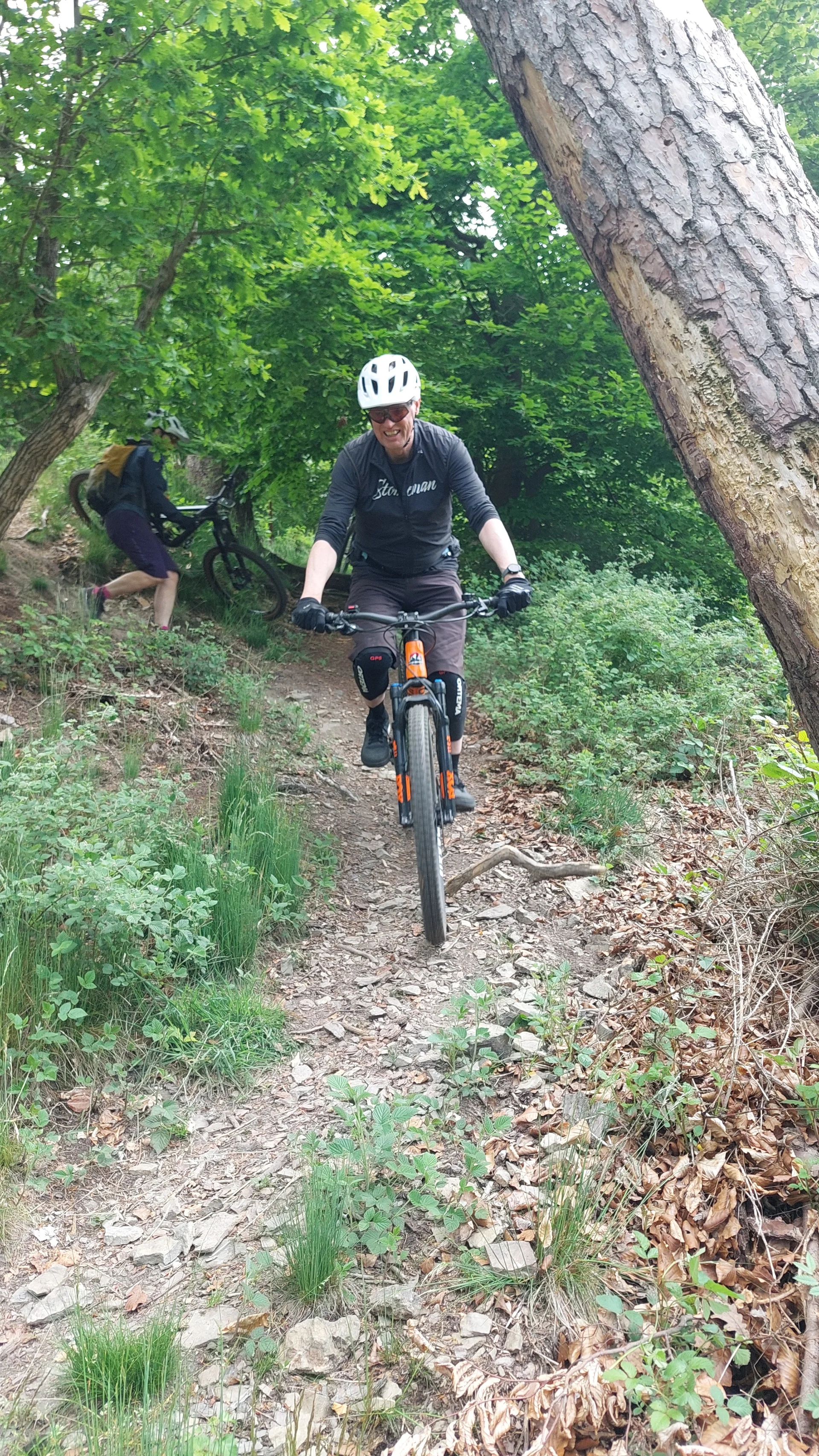 Ein Biker mit weißem Helm fährt vorsichtig eine steinige Passage im Wald hinab. | © DAV Dortmund