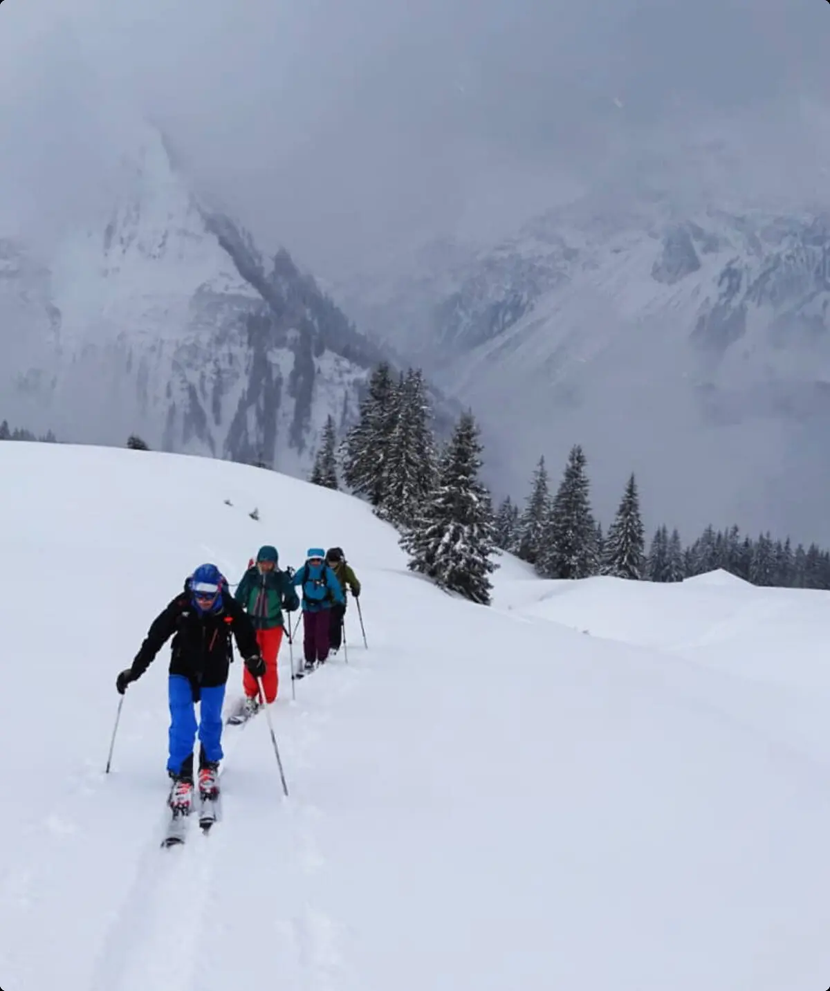 Skitourengruppe geht in einer Reihe durch tiefen Neuschnee, im Hintergrund verschneite Berge. | © DAV Dortmund
