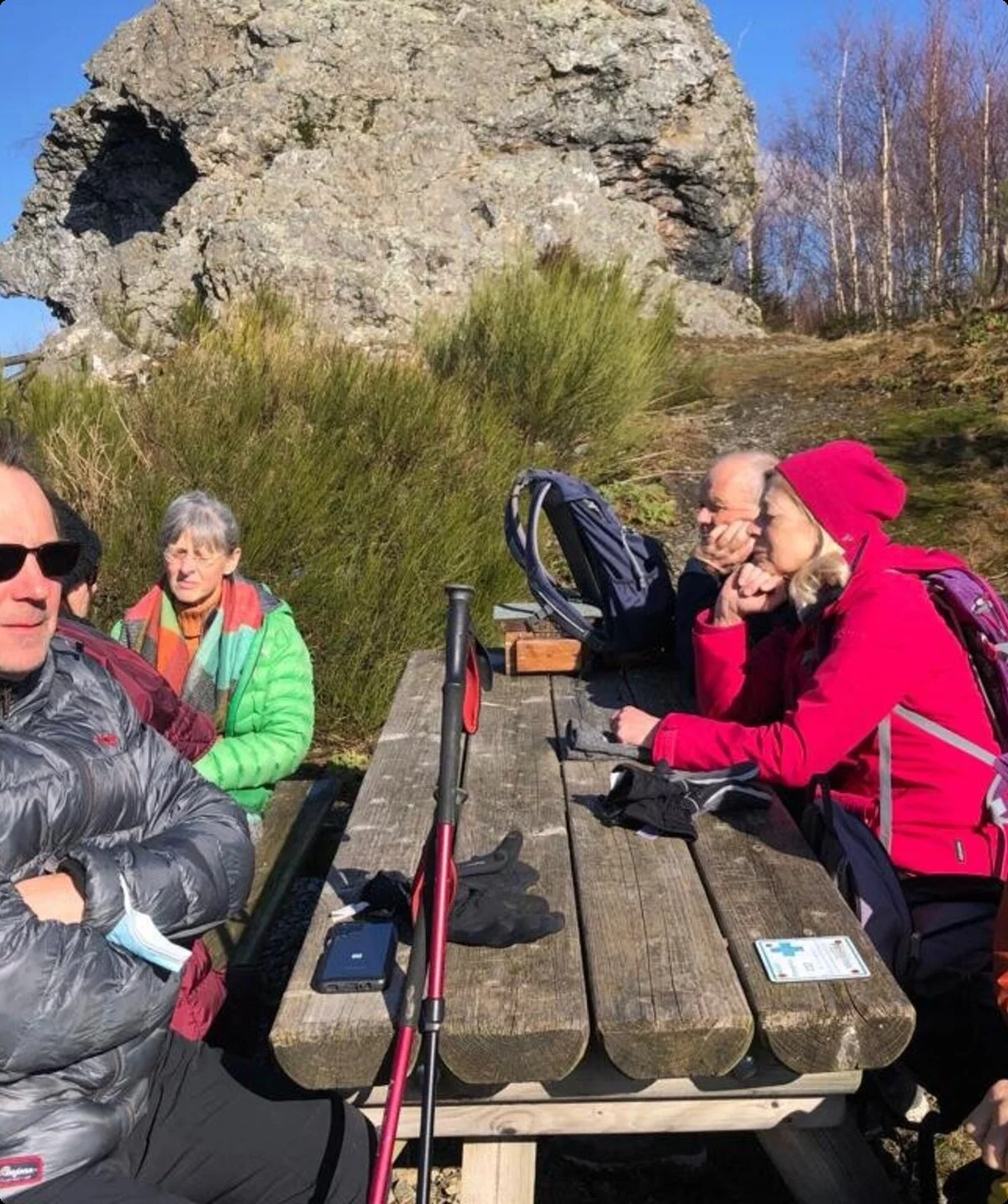 Wandernde sitzen an einem Holztisch mit Blick auf Felsen und genießen die Pause bei sonnigem Wetter. | © DAV Dortmund
