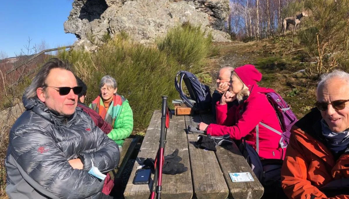 Wandernde sitzen an einem Holztisch mit Blick auf Felsen und genießen die Pause bei sonnigem Wetter. | © DAV Dortmund