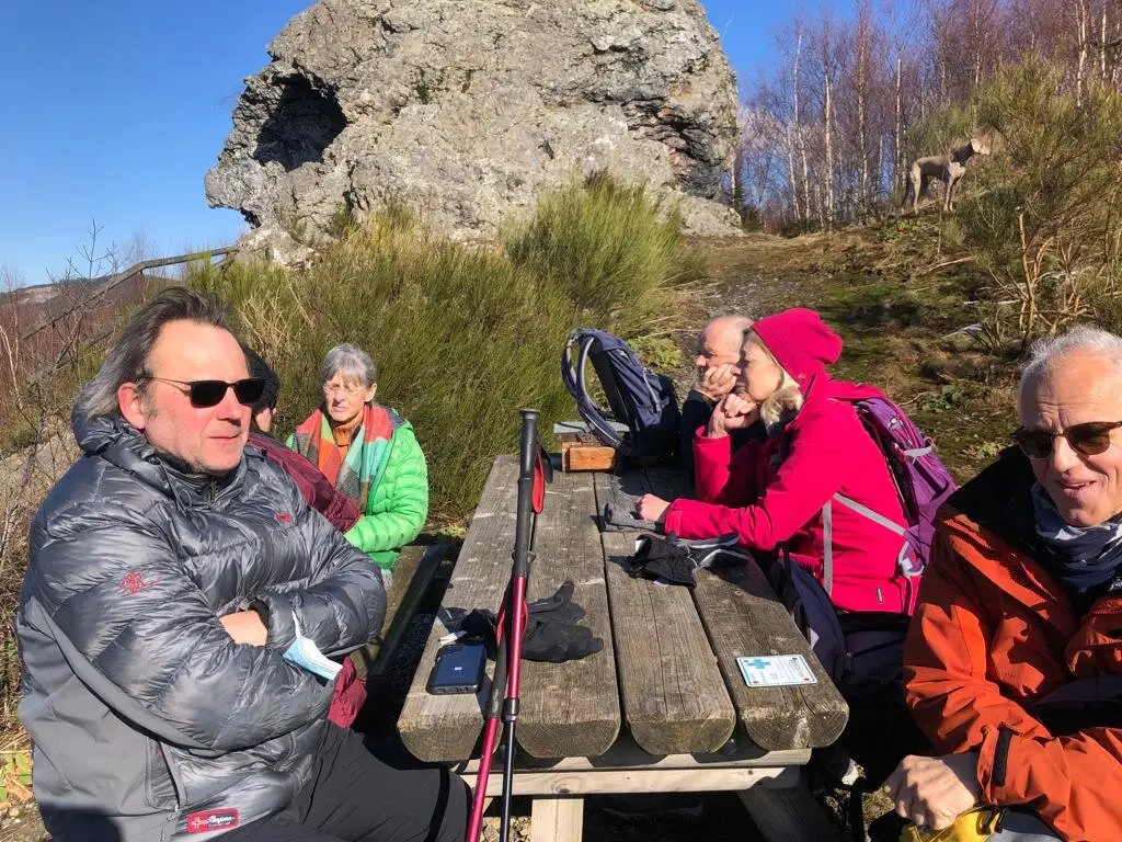 Wandernde sitzen an einem Holztisch mit Blick auf Felsen und genießen die Pause bei sonnigem Wetter. | © DAV Dortmund