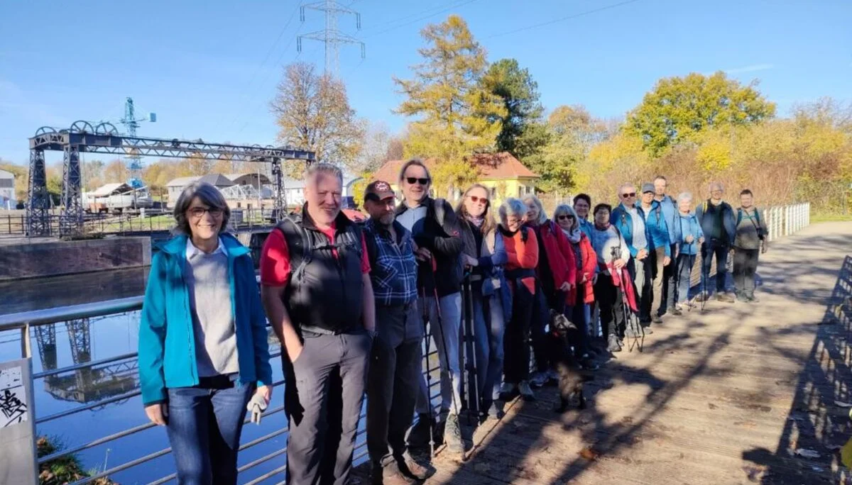 Große Wandergruppe steht auf einem Steg an einem Fluss oder Kanal bei sonnigem Herbstwetter. | © DAV Dortmund