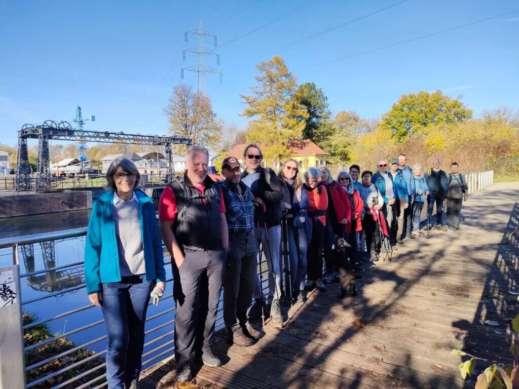 Große Wandergruppe steht auf einem Steg an einem Fluss oder Kanal bei sonnigem Herbstwetter. | © DAV Dortmund