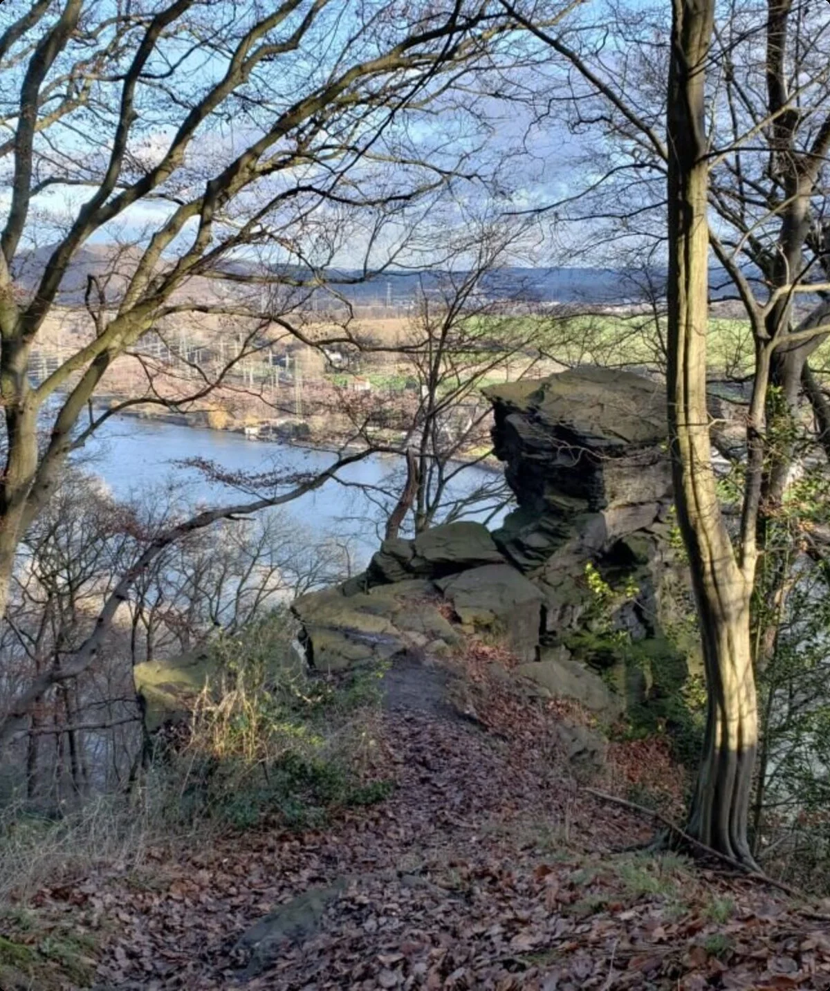 Blick durch kahle Bäume auf einen Felsen oberhalb eines breiten Flusstals bei Winterlicht. | © DAV Dortmund