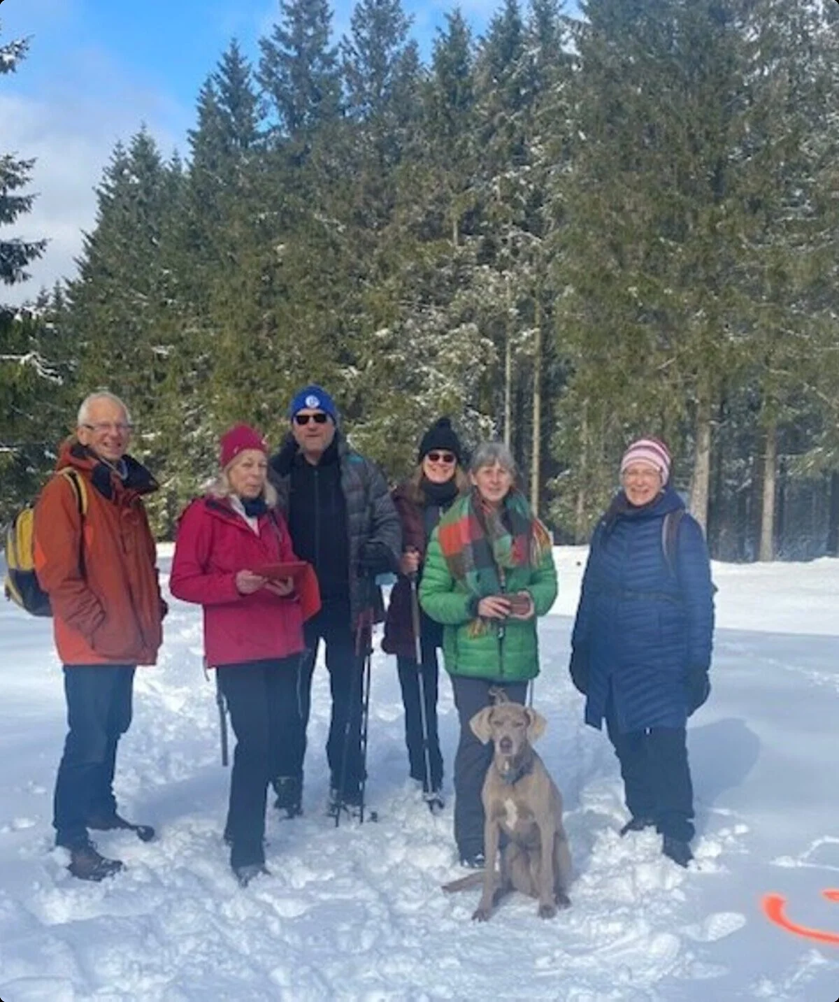 Sieben Personen und ein Hund stehen im Schnee auf einem Weg im Wald, im Vordergrund ein Smiley im Schnee. | © DAV Dortmund