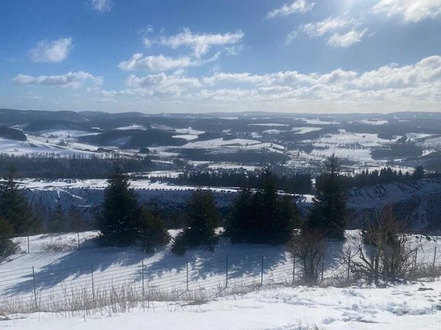 Schneebedeckte Hügellandschaft mit Wäldern und weitem Blick unter blauem Himmel mit Wolken. | © DAV Dortmund