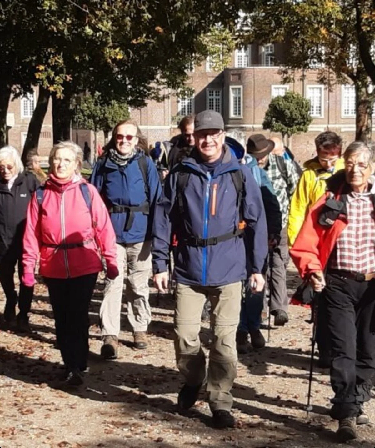 Gruppe von Wander*innen läuft gemeinsam lachend auf einem Weg durch einen grünen Stadtpark. | © DAV Dortmund