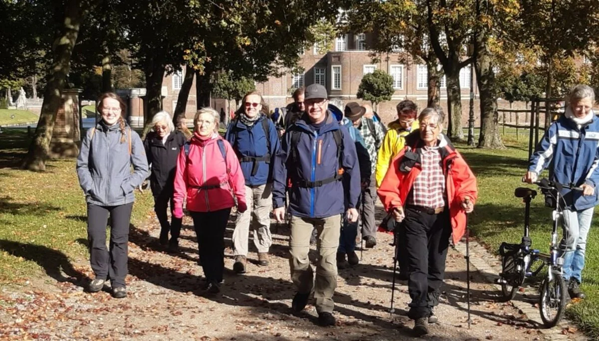 Gruppe von Wander*innen läuft gemeinsam lachend auf einem Weg durch einen grünen Stadtpark. | © DAV Dortmund