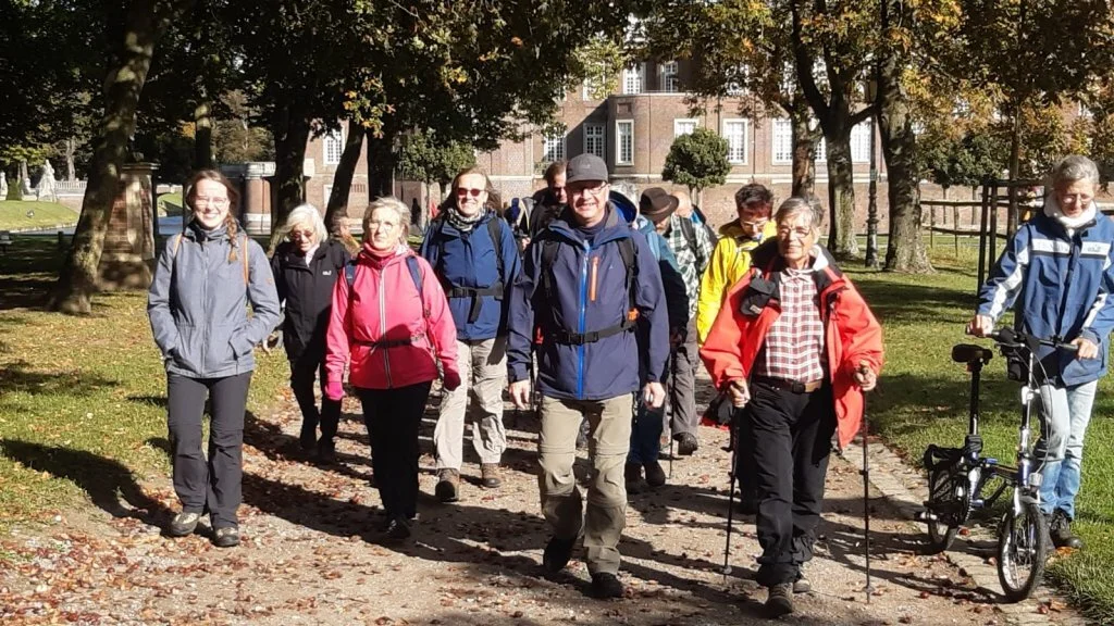 Gruppe von Wander*innen läuft gemeinsam lachend auf einem Weg durch einen grünen Stadtpark. | © DAV Dortmund