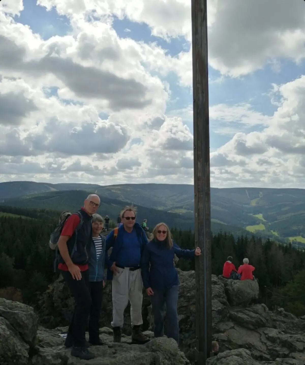 Vier Wander*innen posieren bei bewölktem Himmel neben einem hohen Holzkreuz auf einem Berggipfel. | © DAV Dortmund