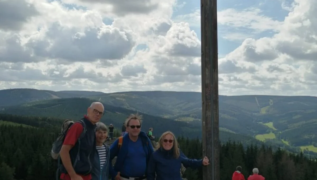 Vier Wander*innen posieren bei bewölktem Himmel neben einem hohen Holzkreuz auf einem Berggipfel. | © DAV Dortmund