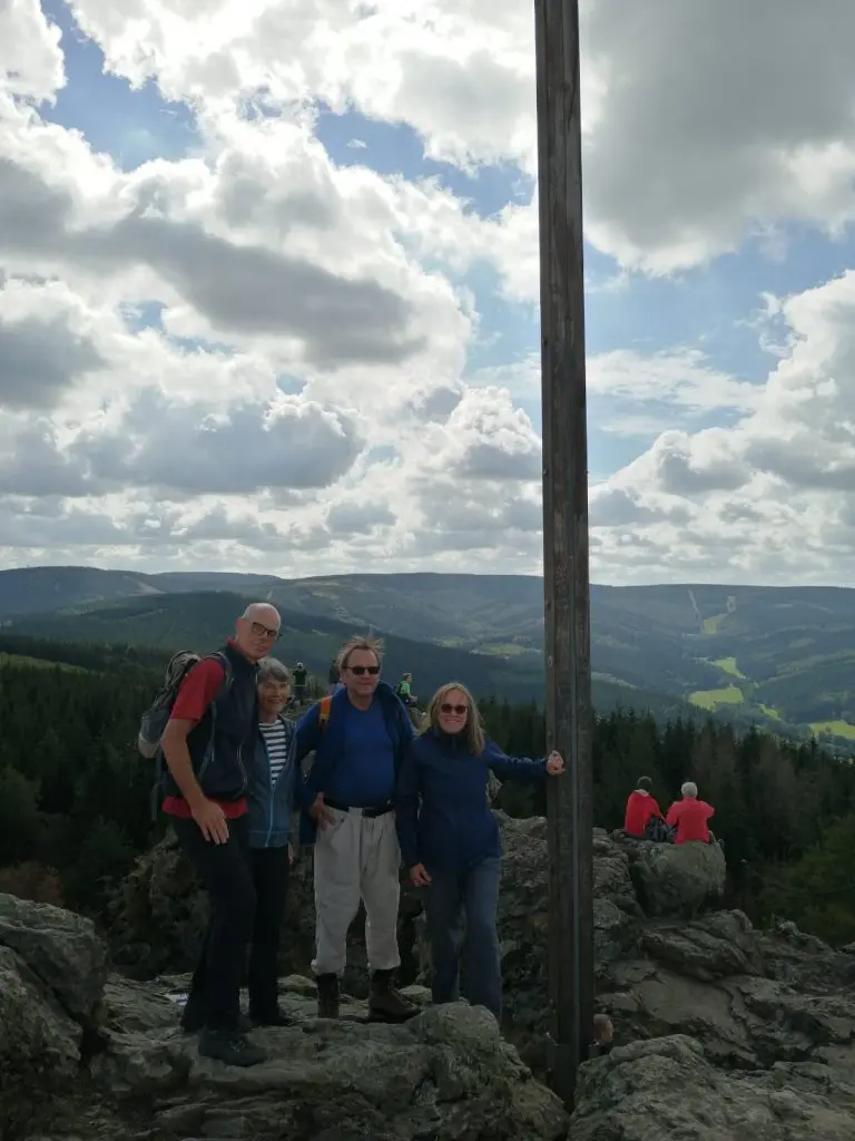 Vier Wander*innen posieren bei bewölktem Himmel neben einem hohen Holzkreuz auf einem Berggipfel. | © DAV Dortmund
