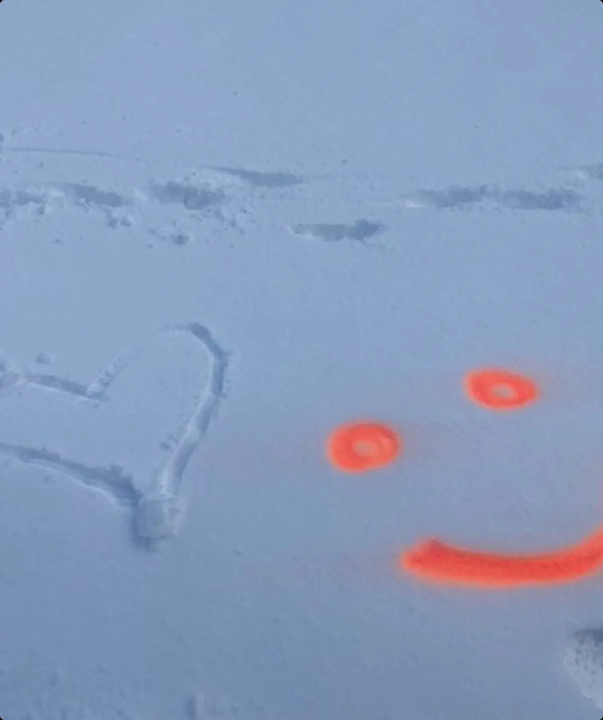 Ein Herz wurde in den Schnee gezeichnet, daneben ein orangefarbenes Smiley aus Sprühfarbe. | © DAV Dortmund
