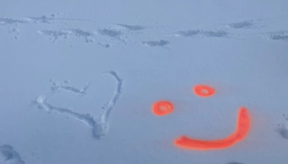 Ein Herz wurde in den Schnee gezeichnet, daneben ein orangefarbenes Smiley aus Sprühfarbe. | © DAV Dortmund