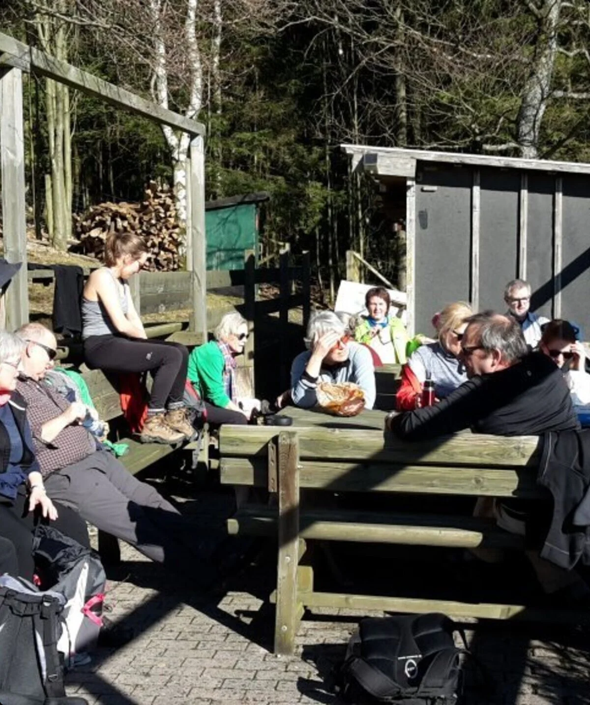 Viele Wandernde sitzen bei sonnigem Wetter an Holztischen im Freien, einige essen. | © DAV Dortmund