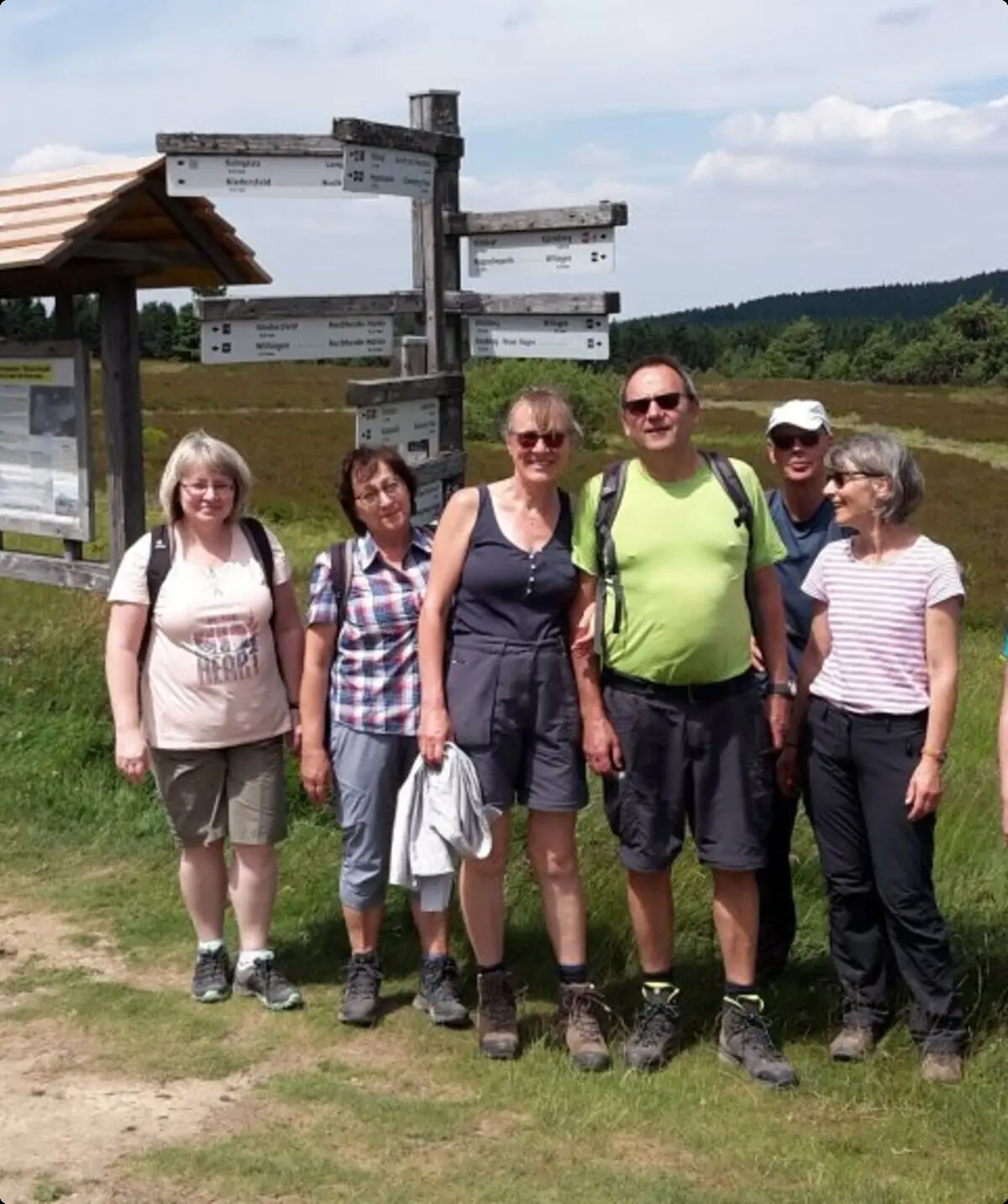 Acht Wandernde stehen vor einem großen Wanderschild auf einem Feldweg. | © DAV Dortmund