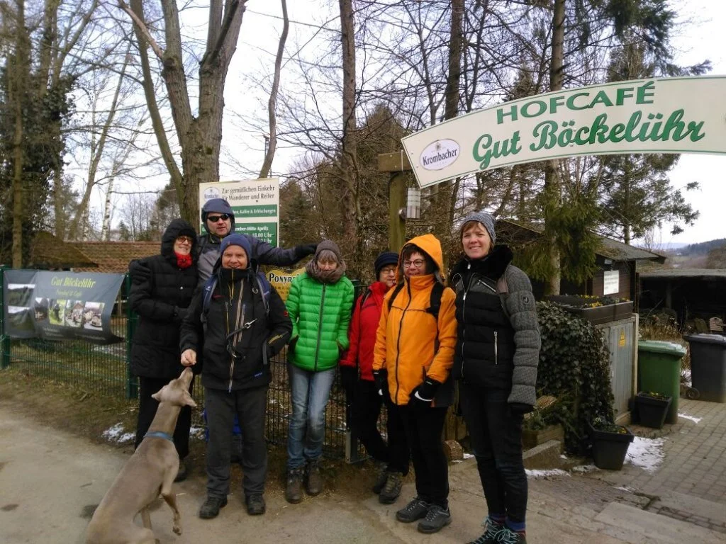 Acht Wandernde mit Hund stehen vor dem Schild eines Landcafés „Gut Böckelühr“. | © DAV Dortmund