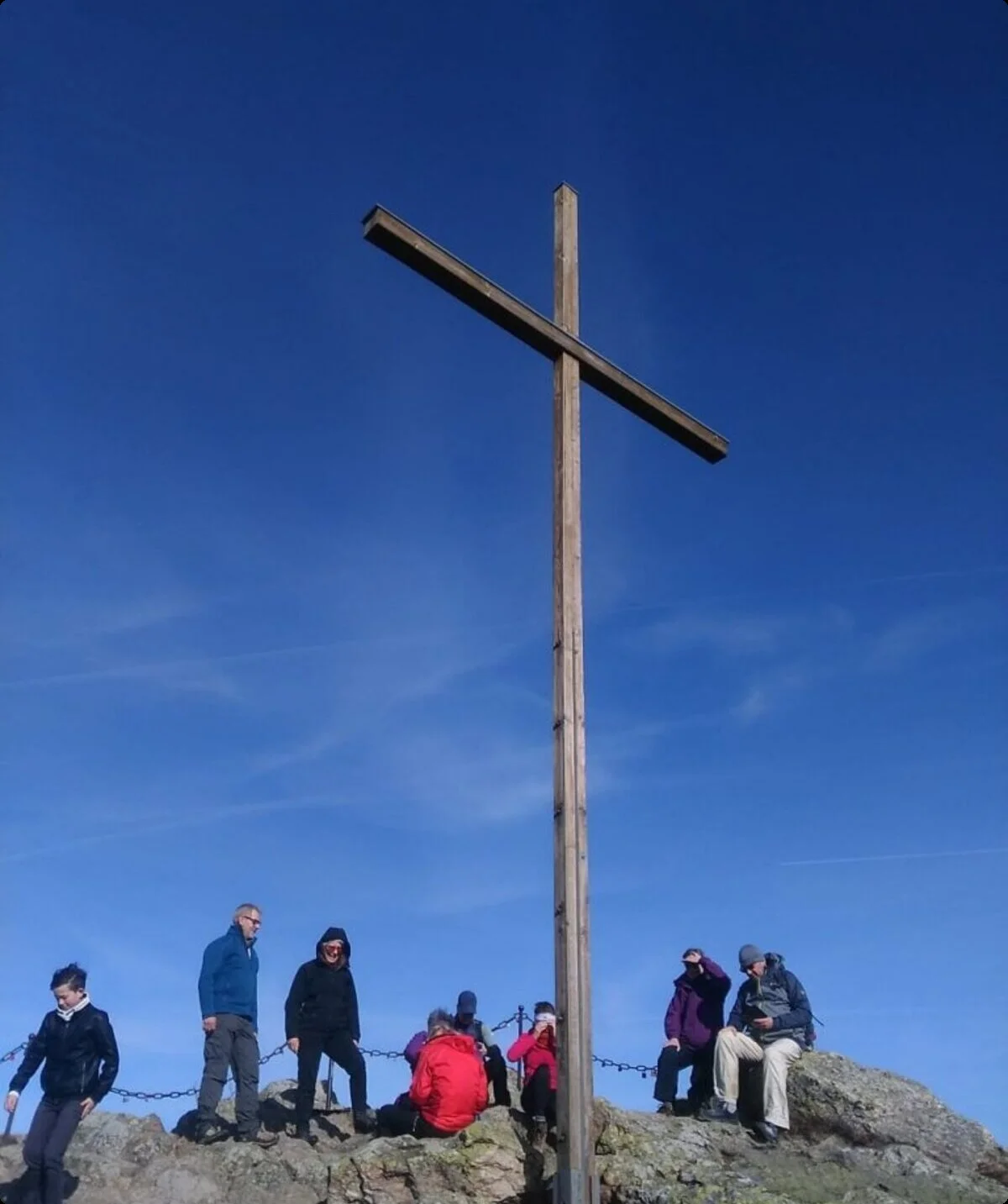 Wandergruppe auf felsigem Gipfel mit großem Holzkreuz und tiefblauem Himmel. | © DAV Dortmund