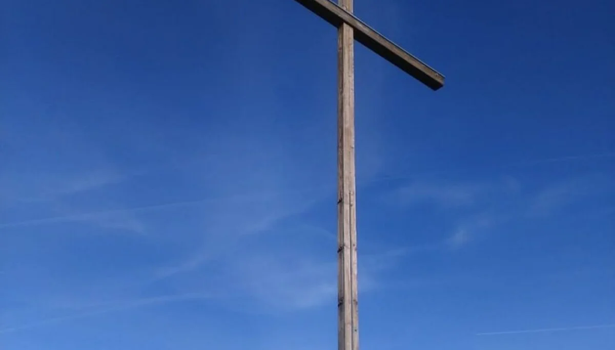 Wandergruppe auf felsigem Gipfel mit großem Holzkreuz und tiefblauem Himmel. | © DAV Dortmund