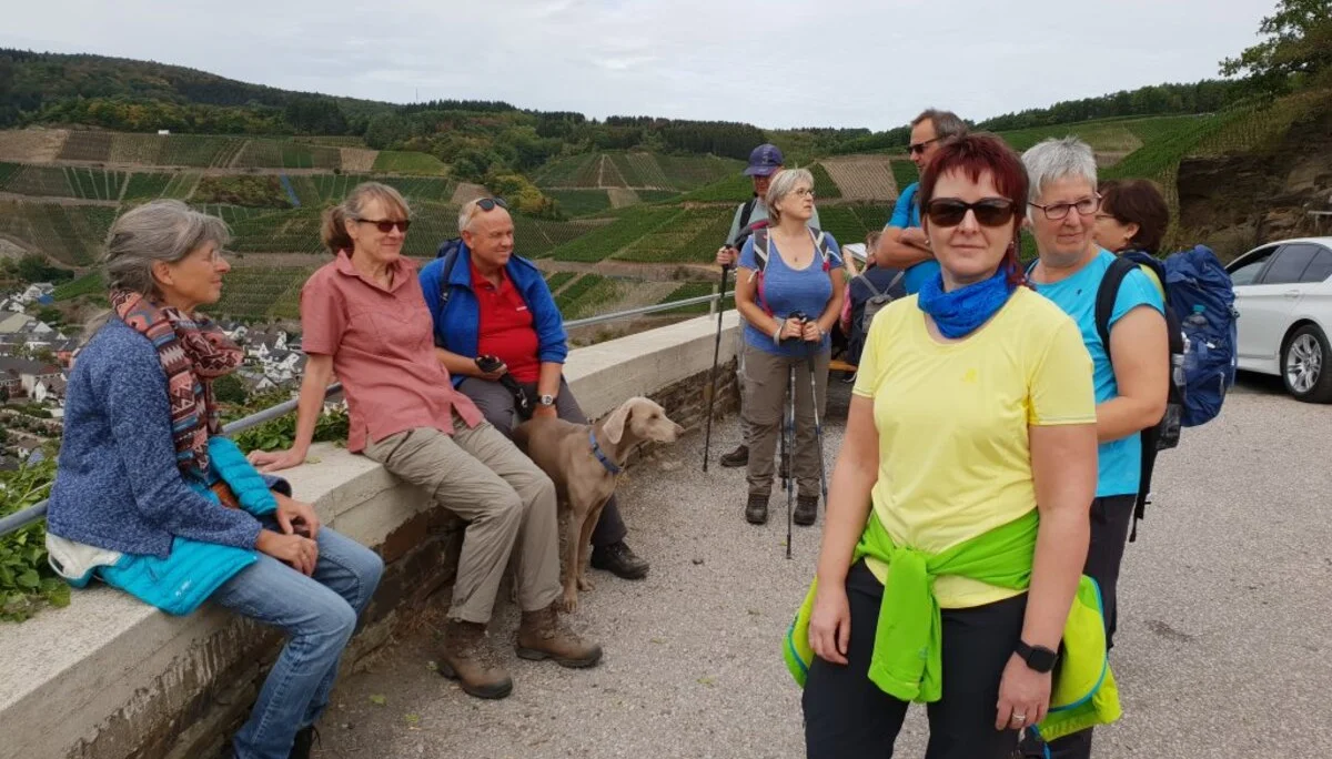Wandergruppe steht an einer Mauer mit Blick auf ein Moseltal mit Weinbergen. | © DAV Dortmund