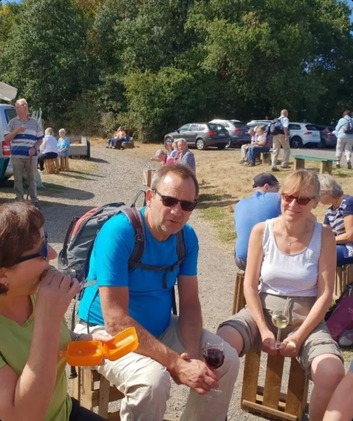 Mehrere Personen sitzen auf Holzbänken bei einem Weinstand und unterhalten sich. | © DAV Dortmund