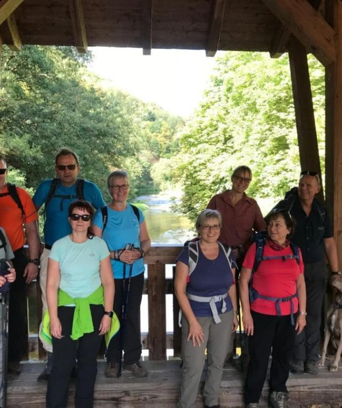 Wanderer mit Rucksäcken und Hund stehen auf einer überdachten Holzbrücke mit Blick auf einen Fluss. | © DAV Dortmund