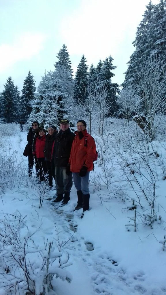 Eine Gruppe Wanderer steht auf einem verschneiten Pfad im Wald. | © DAV Dortmund