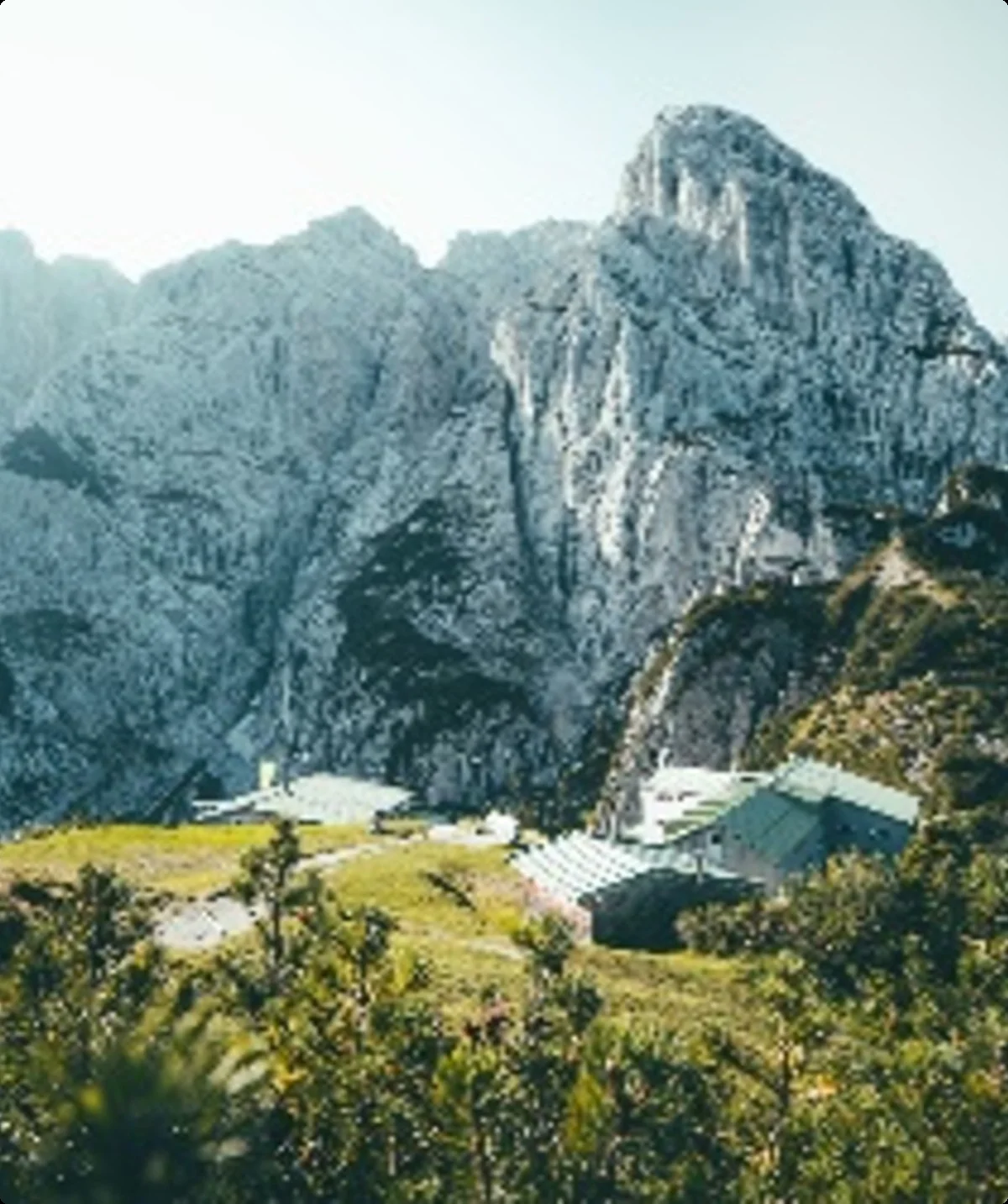 Zwei Berghütten liegen eingebettet zwischen felsigen Bergwänden im Sonnenlicht. | © DAV Dortmund