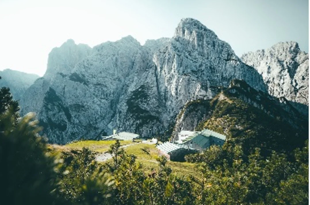 Zwei Berghütten liegen eingebettet zwischen felsigen Bergwänden im Sonnenlicht. | © DAV Dortmund