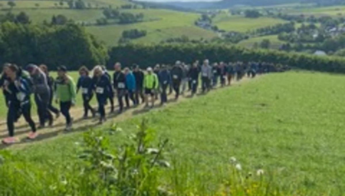 Lange Reihe von Wander*innen zieht sich durch eine hügelige grüne Landschaft. | © DAV Dortmund