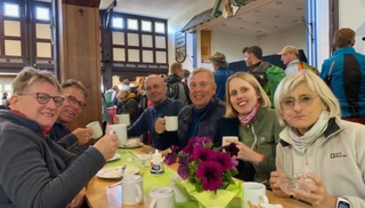 Personengruppe sitzt lachend an einem Tisch in einer Hütte mit Getränken. | © DAV Dortmund