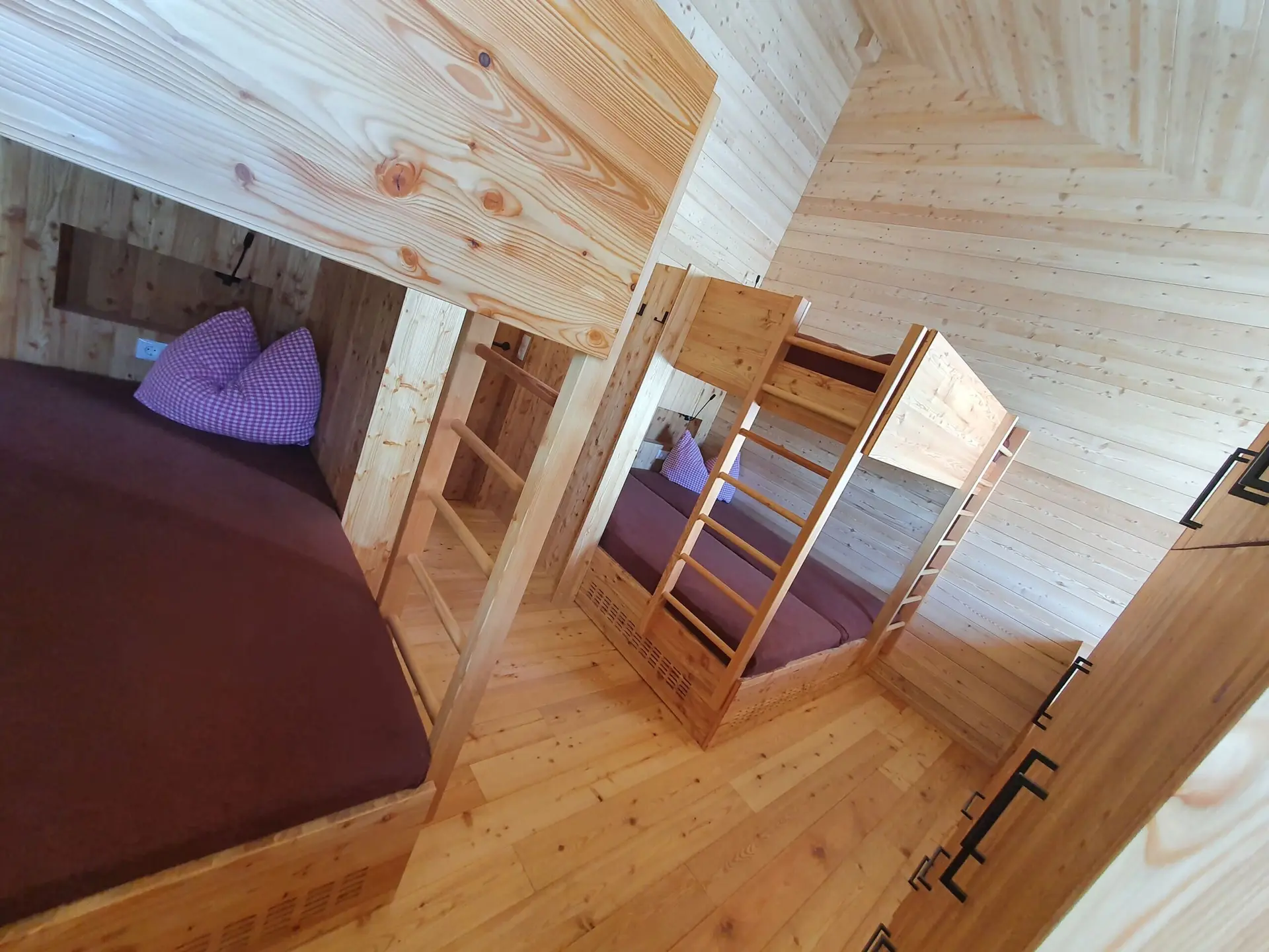 Mehrere Schlafkojen mit Matratzen und Holzrahmen in einem modern eingerichteten Gruppenraum. | © DAV Dortmund