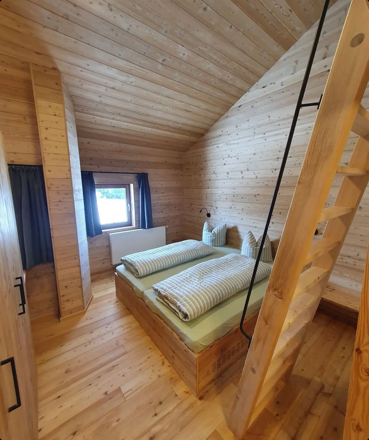 Ein helles Zimmer mit Holzwänden und Doppelbett, darüber eine Galerie mit Holzleiter erreichbar. | © DAV Dortmund