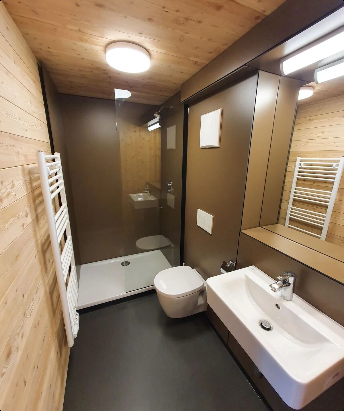 Badezimmer mit bodengleicher Dusche, WC, Waschbecken und heller Beleuchtung in Holzoptik. | © DAV Dortmund