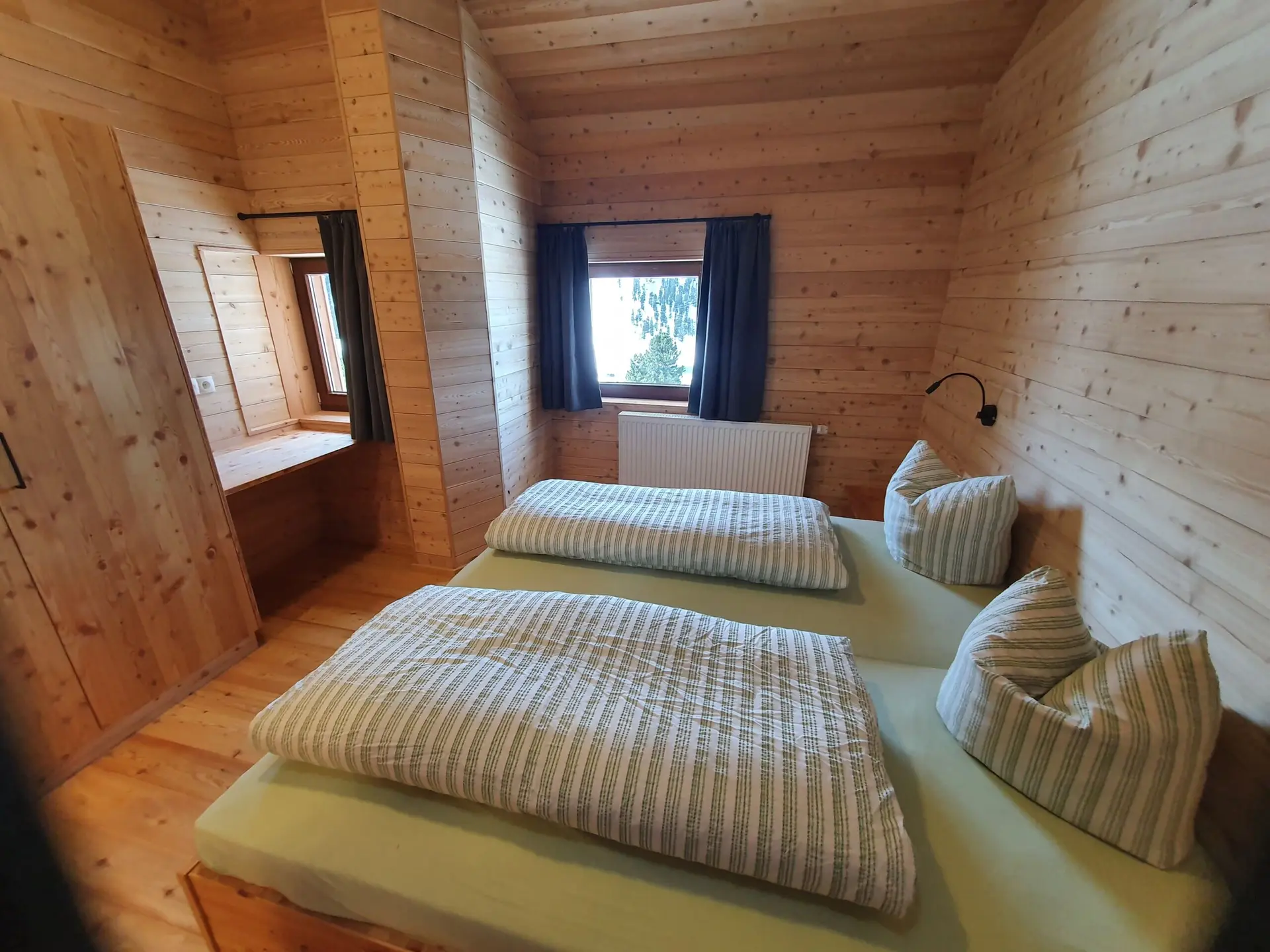 Gemütliches Holzschlafzimmer mit Doppelbett, Fensterblick und klarer Raumstruktur. | © DAV Dortmund