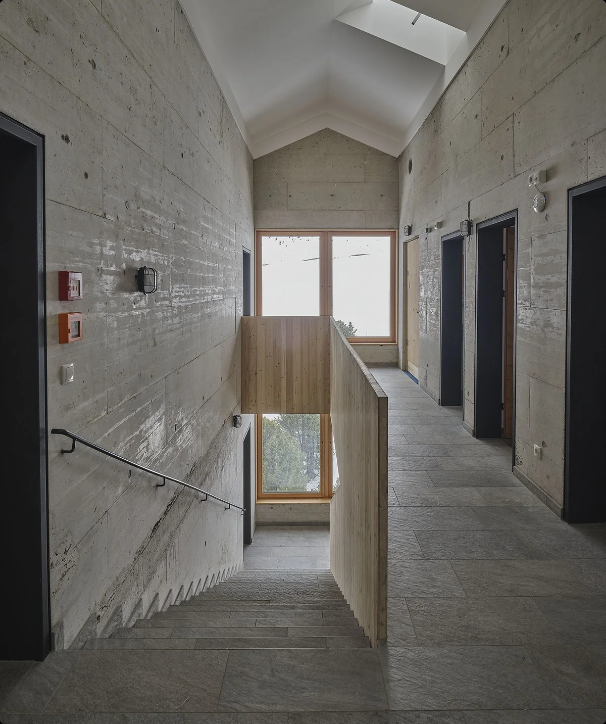 Ein breiter Flur mit Sichtbeton, mehreren Türen und einem großen Fenster am Ende. | © DAV Dortmund