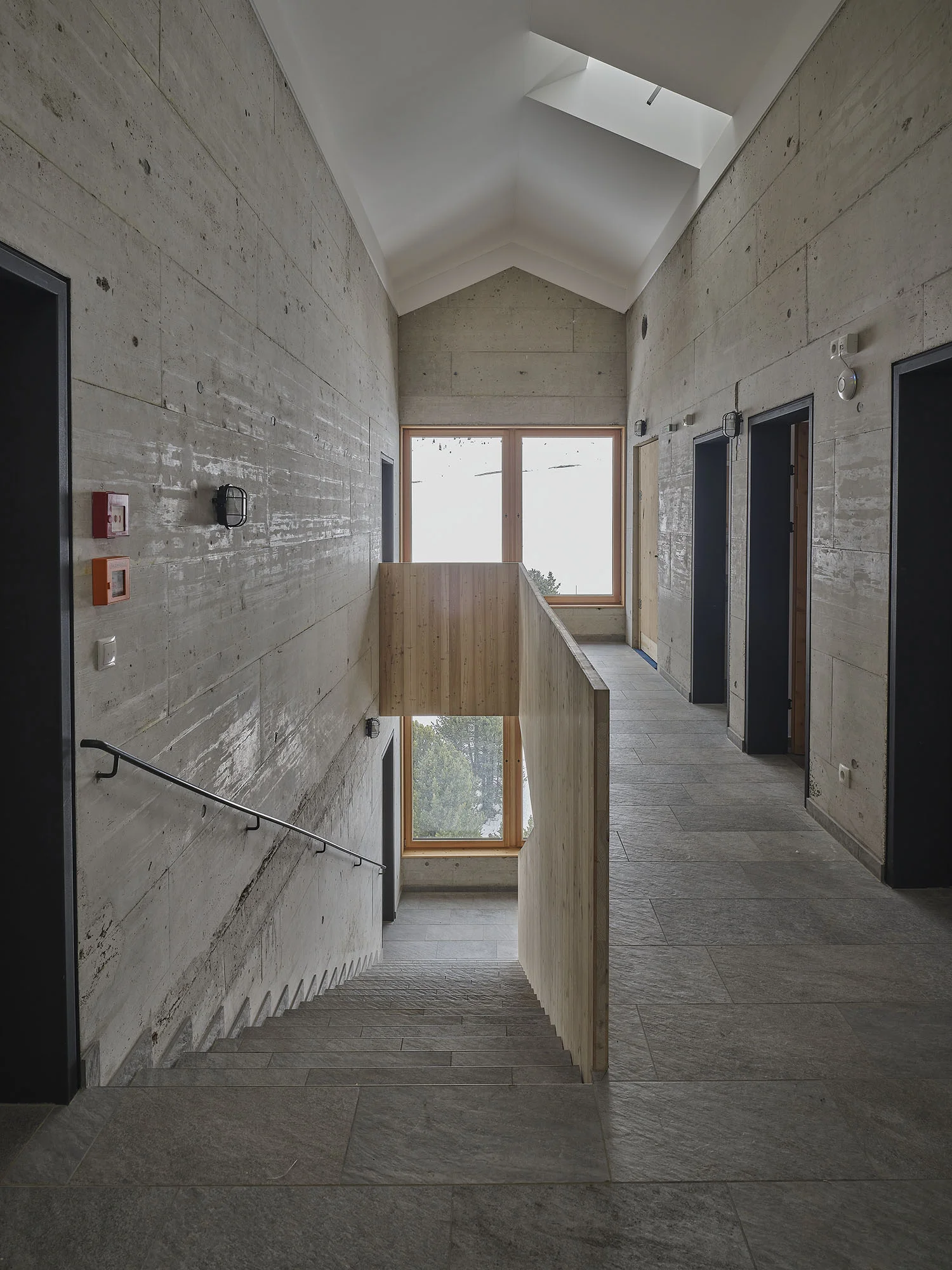 Ein breiter Flur mit Sichtbeton, mehreren Türen und einem großen Fenster am Ende. | © DAV Dortmund