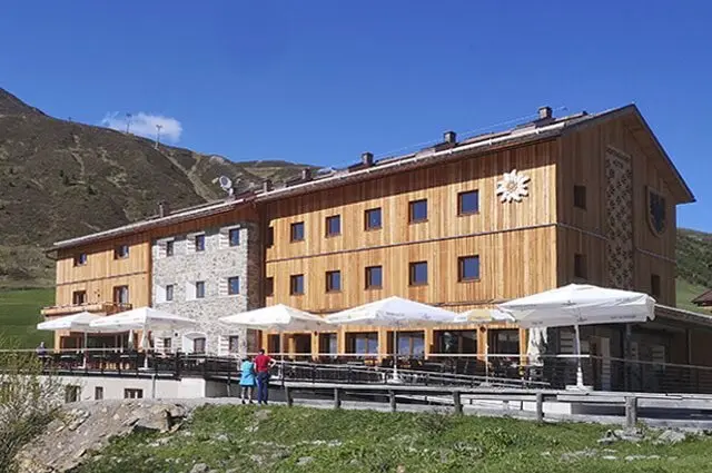 Die Dortmunder Hütte mit Holzfassade, Sonnenschirmen und Bergpanorama im Hintergrund. | © DAV Dortmund