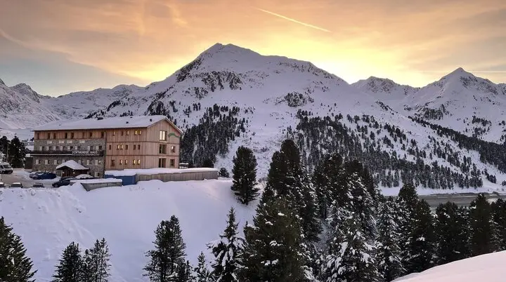 Berghütte in verschneiter Alpenlandschaft bei Sonnenuntergang. | © H. Schimmelfelder