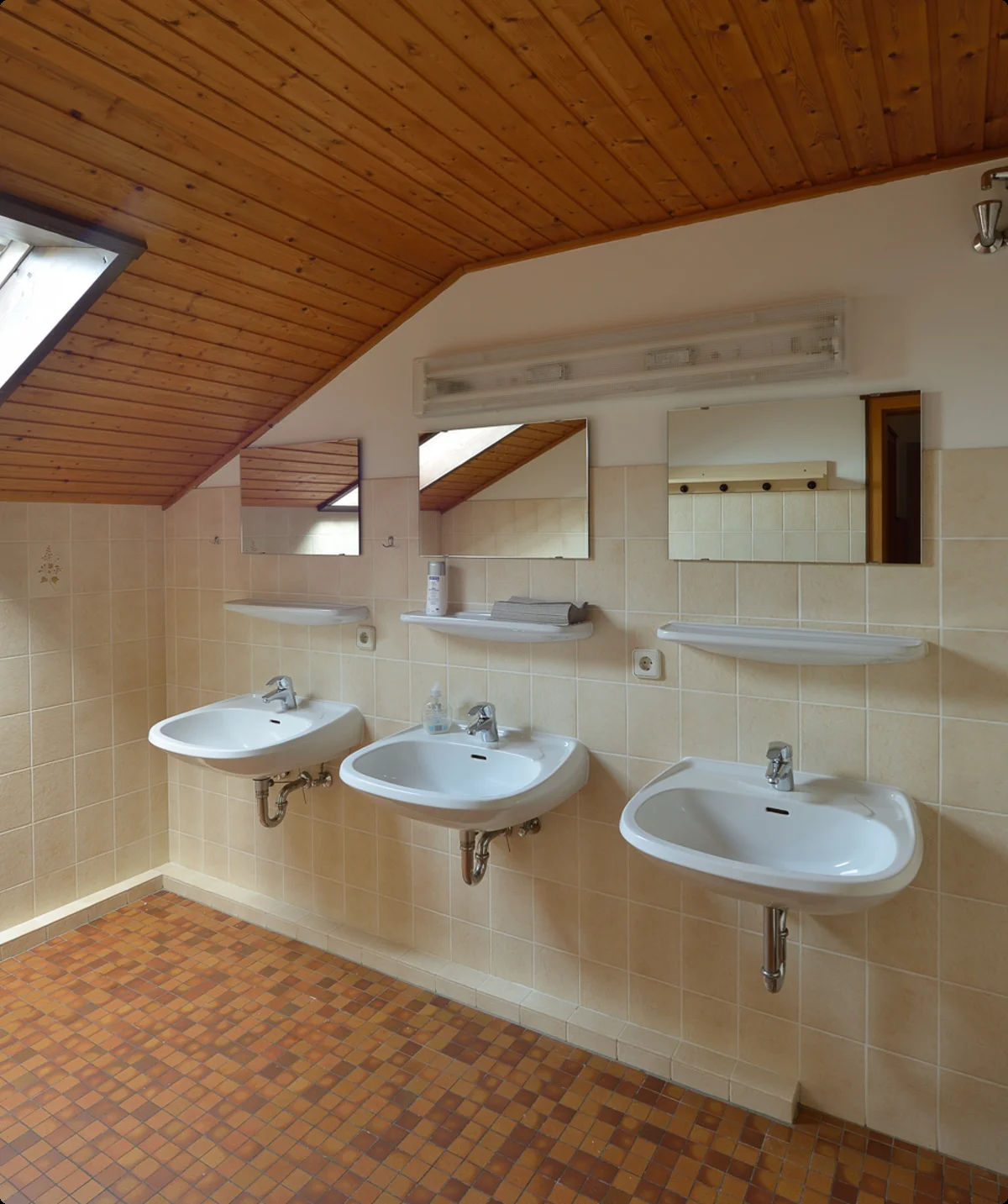 Drei Waschbecken mit Spiegeln in einem hellen Waschraum mit Dachschräge und Holzdecke. | © DAV Dortmund