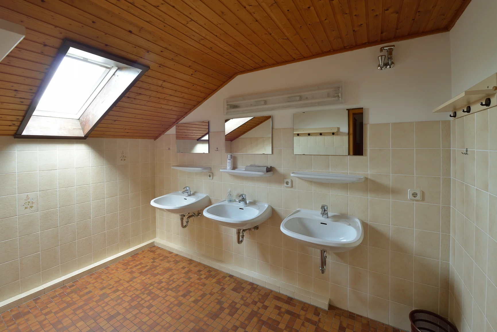 Drei Waschbecken mit Spiegeln in einem hellen Waschraum mit Dachschräge und Holzdecke. | © DAV Dortmund