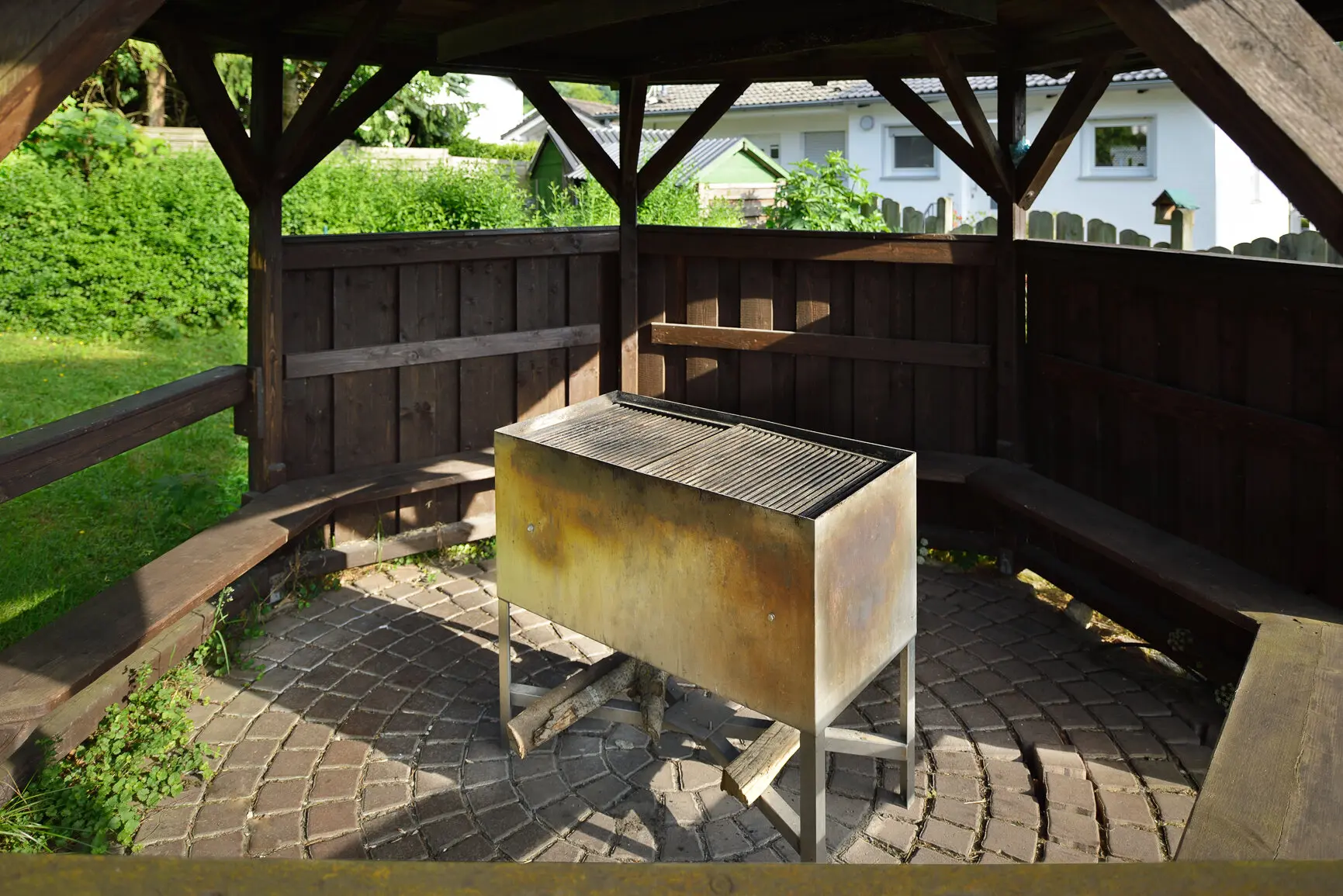 Ein Grill steht unter einem hölzernen Pavillon mit umlaufender Sitzbank im Freien. | © DAV Dortmund