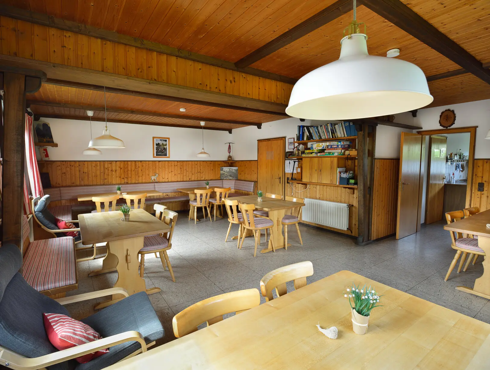 Ein heller Gastraum mit Holzmöbeln und mehreren Tischen in einer Berghütte, gemütlich eingerichtet. | © DAV Dortmund