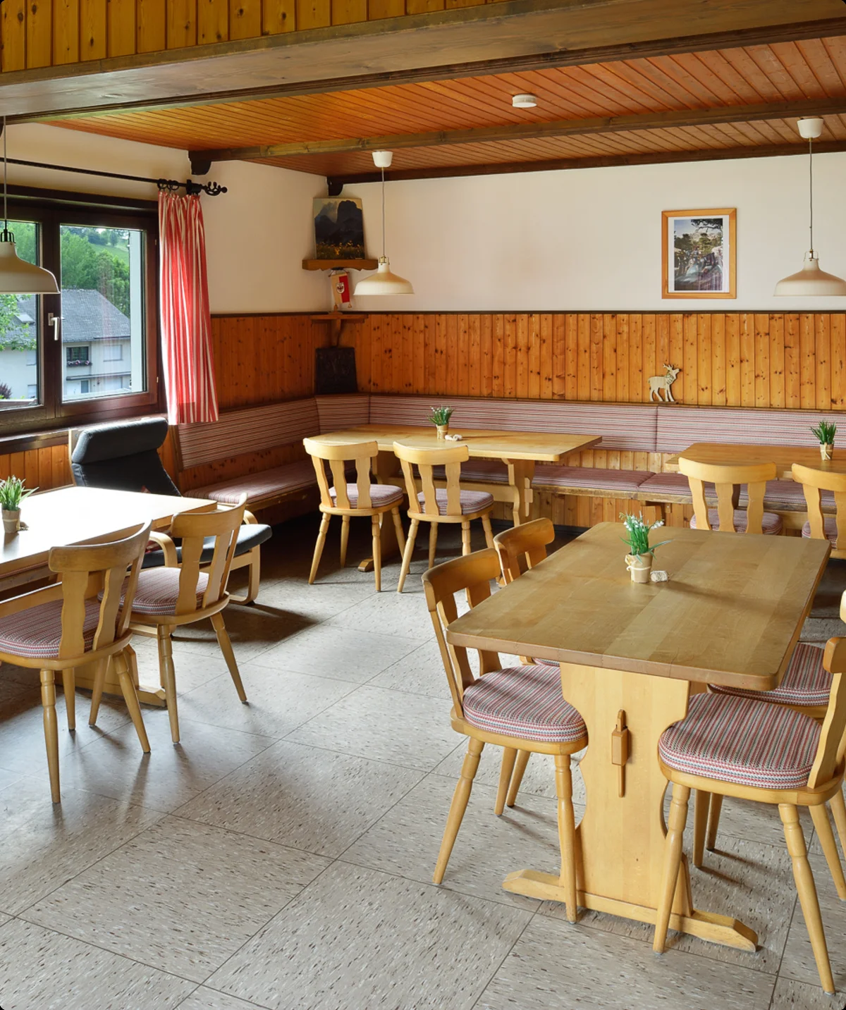 Ein traditioneller Gastraum mit Holzbänken an der Wand, Tischen und kleiner Dekoration. | © DAV Dortmund